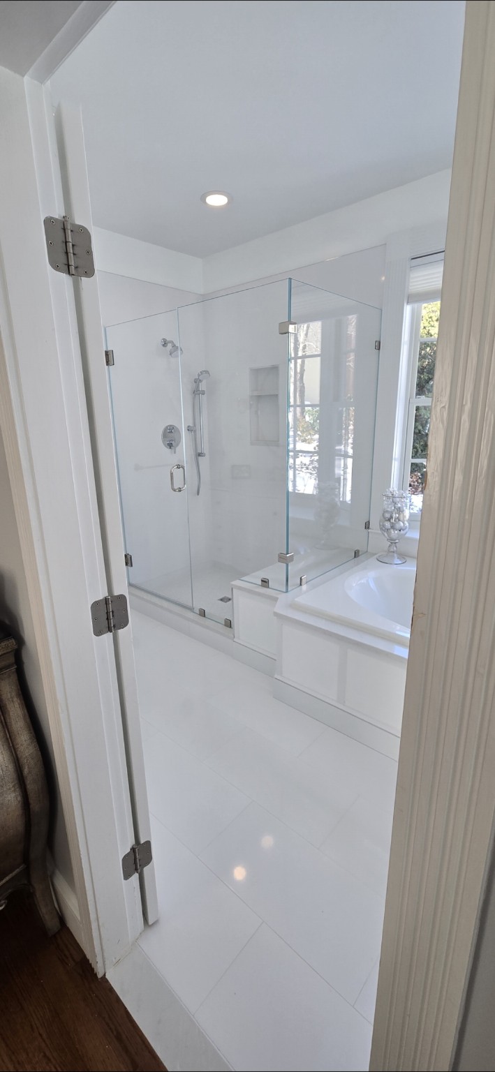 Bright white bathroom with glass shower enclosure and tub
