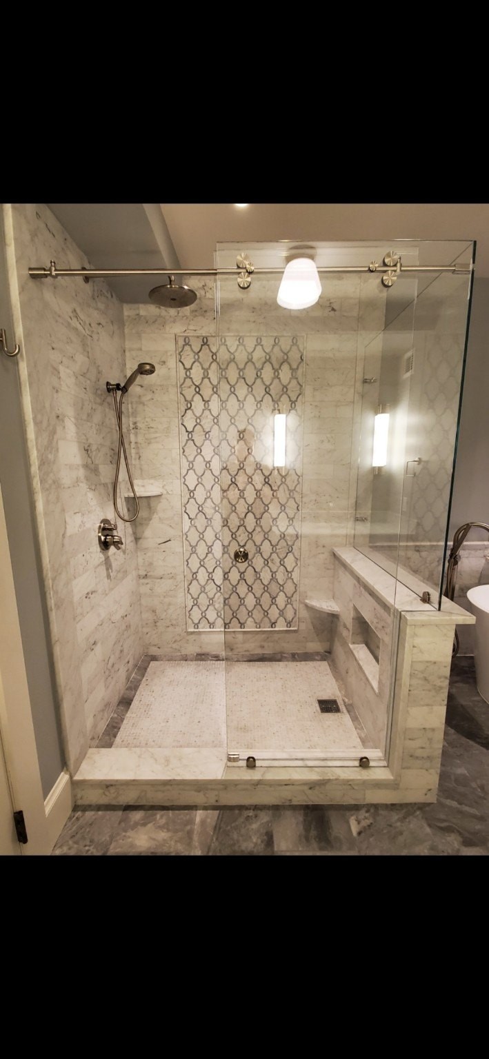 Marble shower with custom accent panel and glass enclosure