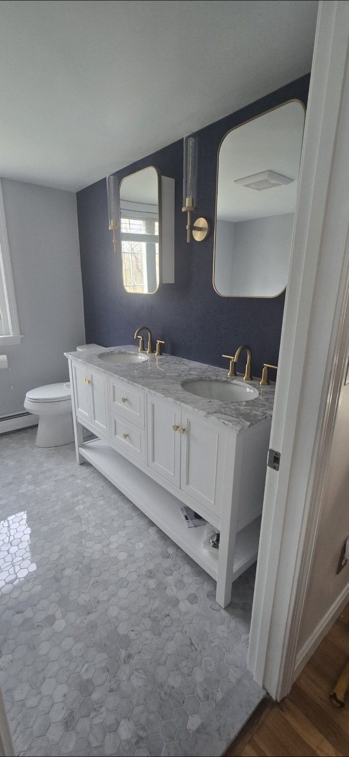 Double vanity bathroom with marble floor and brass fixtures