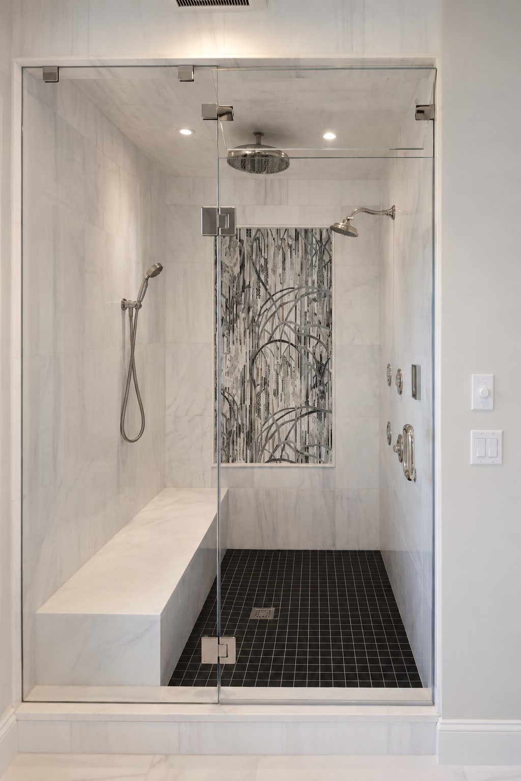 Marble shower with built-in bench and decorative tile feature